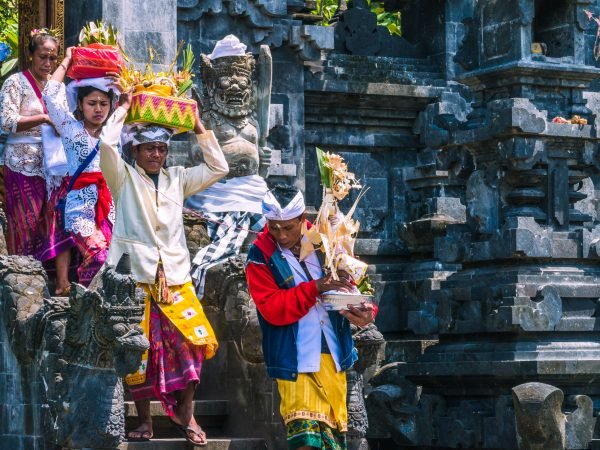 GOA LAWAH, BALI, INDONESIA - November 3, 2016: Balinese people in traditional clothes carry bless gift after ceremony at Pura Goa Lawah temple, Bali, Indonesia.