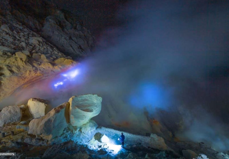 Worker working at mountain and smoking mine mountain in the morning at Kawah Ijen volcano East Java Indonesia with milky way night sky background