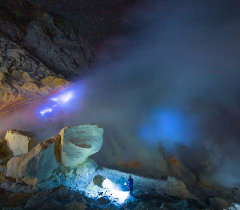 Worker working at mountain and smoking mine mountain in the morning at Kawah Ijen volcano East Java Indonesia with milky way night sky background